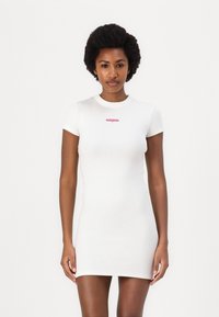 White ribbed bodycon dress with short sleeves, featuring a small pink logo on the chest. Smooth texture and fitted silhouette.