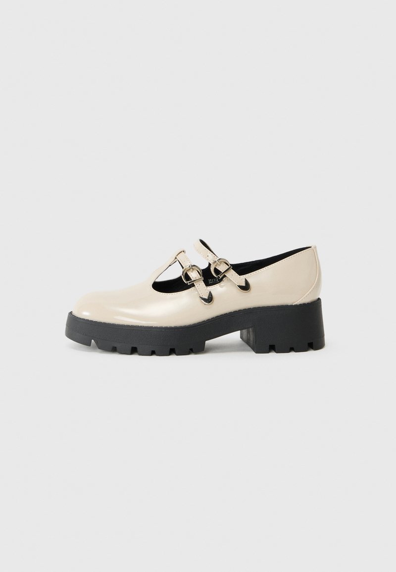 Zapatos Mary Jane de charol beige con punta redonda, doble correa con hebillas y suela gruesa de goma negra.
