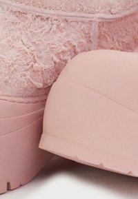 Rózsaszín csizmák texturált velúrból készült kivitelben, sima gumi talppal, lekerekített formával és jellegzetes varrási részletekkel.