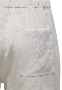 Helle graue Baumwollshorts mit einem elastischen Bund und einer einzelnen aufgesetzten Tasche auf der Rückseite, mit sichtbaren Steppdetails.
