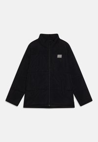 Veste noire matelassée avec fermeture éclair intégrale à l'avant, col montant, deux poches latérales et une petite étiquette rectangulaire sur la poitrine.