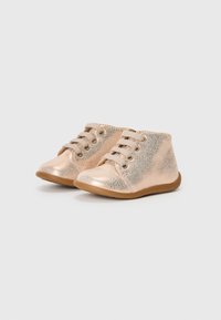 Zapatos de bebé metálicos en color rosa dorado con una textura agrietada, puntera redondeada y dos juegos de cordones. Suela de goma suave para mayor comodidad.