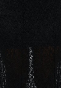 Tissu en dentelle noire avec des motifs floraux complexes et une fente verticale transparente au centre révélant un matériau plus clair en dessous.