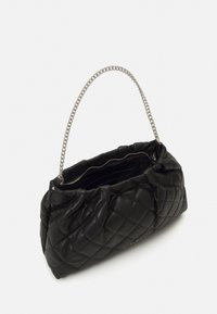 Borsa a mano in pelle nera trapuntata con manico a catena argentata, chiusura con cerniera e un aspetto morbido e imbottito. Il design interno è minimalista.