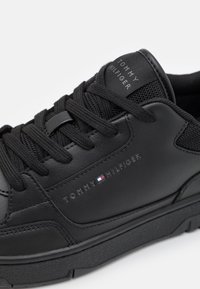 Baskets en cuir noir avec une langue en mesh texturé, un design à lacets et un logo embossé. Semelle en caoutchouc avec des rainures discrètes pour une meilleure adhérence.