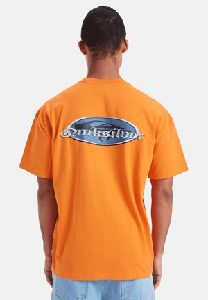 Orange bomulds T-shirt med et stort blåt og sølv logo på ryggen, afslappet pasform og korte ærmer.