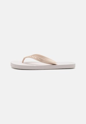 Lichtroze flip-flop met een gestructureerde zool en verhoogd logo op de band. Plat ontwerp met een gladde afwerking en minimalistische vorm.