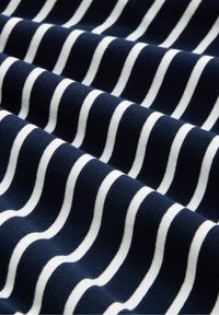 Marineblauer Stoff mit weißen wellenförmigen Streifen, der eine weiche Textur aufweist. Die Streifen variieren in der Breite und schaffen ein dynamisches Muster über das Material.