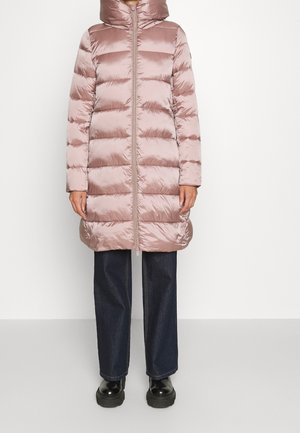 Longue doudoune mauve brillante avec quilting horizontal, col montant, fermeture éclair à l'avant, associée à un jean large foncé et des chaussures noires.