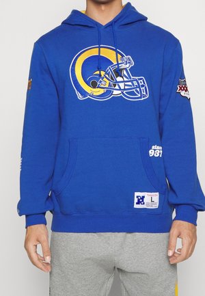 Niebieska bluza z kapturem z dużym żółto-białym logo kasku futbolowego, łatką Super Bowl na rękawie, kieszenią z przodu, noszona przez osobę w szarych spodniach.