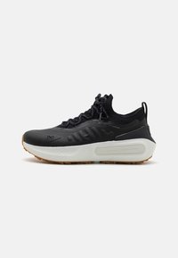 Black athletic shoe with a textured upper, sock-like collar, gray laces, and a white midsole featuring a patterned design and gum outsole.