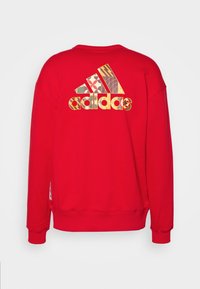Felpa rossa con un grande logo Adidas colorato e con motivi geometrici sul retro. Design classico con colletto girocollo e polsini a coste.
