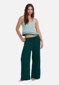 Twee-delig outfit met een lichtgroene geribbelde crop top met een gestreepte onderrand en donkergroene brede gebreide broek met een touwtje in de taille.