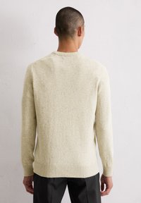 Hellbeige Wollpullover mit strukturiertem Finish, gerippten Bündchen und Saum. Rundhalskragen, taillierte Silhouette und lange Ärmel.