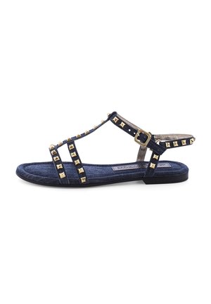 Marineblauwe sandalen met gouden piramide-studs, platte zool, T-band ontwerp, verstelbare gesp, denimachtige textuur.