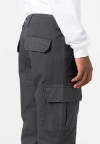 Donkergrijze cargobroek met meerdere klepzakken en een stevige stof, met een getailleerde pasvorm en een gestroomlijnd ontwerp.