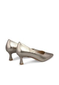 Metaliczne srebrne czółenka na niskim obcasie z szpiczastym noskiem i gładką fakturą. Wyposażone w smukły design i zwężający się obcas zapewniający stabilność.