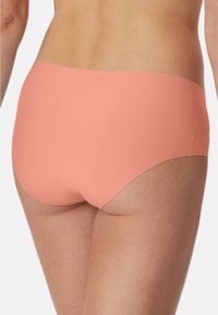 Peach fabric brief with a smooth texture and seamless design, featuring an elastic waistband and a mid-rise cut.