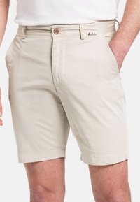Beige katoenen shorts met een knoopsluiting, zijzakken en een klein decoratief Italiaans vlaggetje op de tailleband. Zachte textuur.