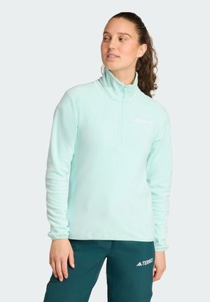 Sudadera de forro polar azul claro con diseño de media cremallera, mangas largas y logotipo bordado en el pecho. Textura suave y corte relajado.