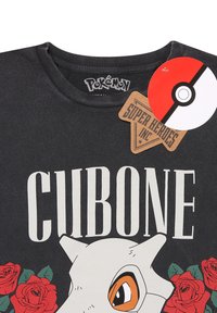 Zwarte katoenen t-shirt met witte tekst "CUBONE" en een afbeelding van een Cubone met rode rozen. Labels bevatten het Pokémon-logo en de branding van Super Heroes Inc.
