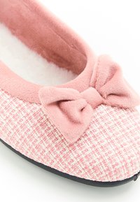 Babbbuccia rosa con upper in tessuto intrecciato a motivo quadrato, un morbido fiocco rosa e una fodera interna soffice.