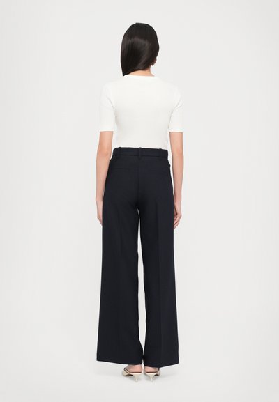 Wide-leg navy trousers with a tailored fit, adorned with back pockets and a smooth waistband, paired with a fitted white top.