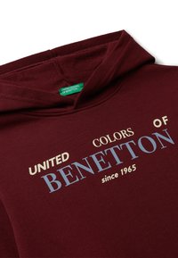 Felpa bordeaux con una texture morbida, caratterizzata dalla scritta "UNITED COLORS OF BENETTON dal 1965" stampata in colori a contrasto. Design classico del cappuccio.