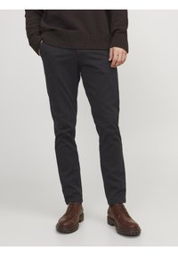 Mörk marinblå chinos i mjukt tyg, med slim fit-design, sidofickor och en ren finish, matchade med bruna snörskor.