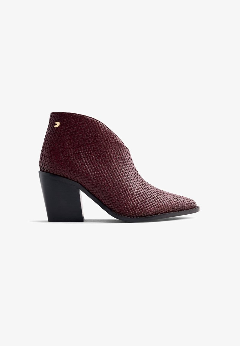 Bottine en cuir tressé bourgogne avec un bout pointu et un talon bloc noir de 7,5 cm. Présente un petit logo doré en accent sur le côté.