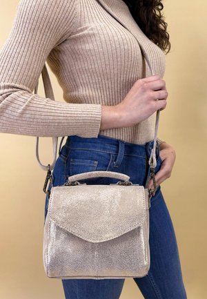 Liten metallisk handväska med en strukturerad form, glittrig yta, övre handtag och justerbar rem, placerad mot en neutral bakgrund.
