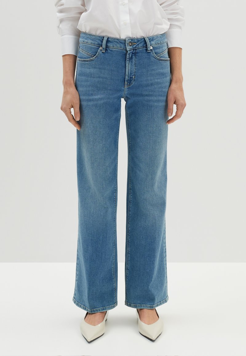 Jean large bleu clair en denim, doté de poches avant, d'une fermeture à bouton et zip, et d'une finition de bas propre.