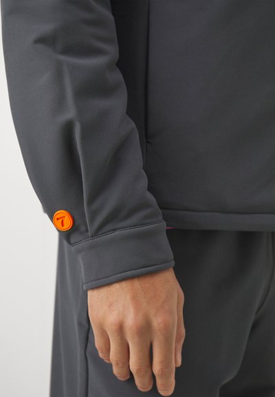 Gray long-sleeve shirt featuring a cuff with an orange button and a smooth texture. Visible stitching at the wrist.