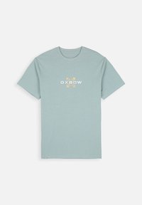 T-shirt bleu clair à manches courtes. Présente un logo Oxbow blanc et jaune sur le devant. Fabriqué en tissu doux avec un col rond.