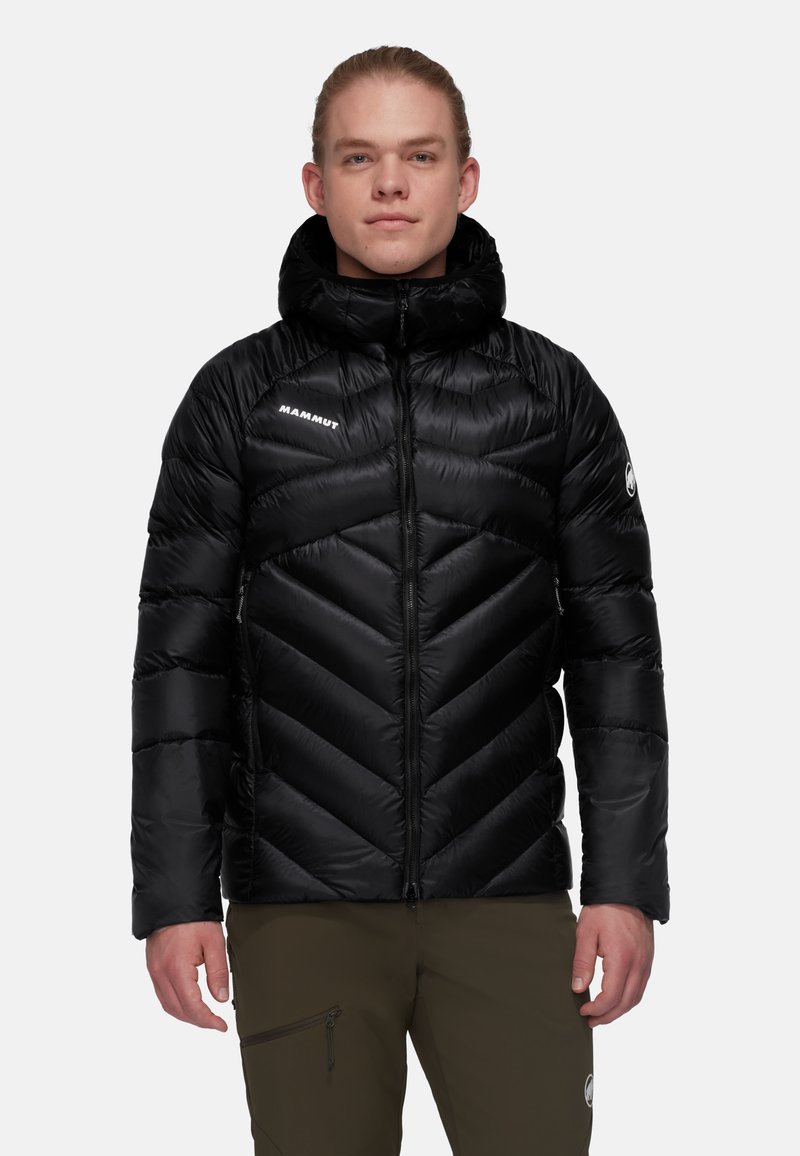 Svart isolerad puffjacka med en chevrondesign, hög krage och dragkedjestängning. Har en logotyp på vänster bröst och en dragkedjeficka på ena ärmen.