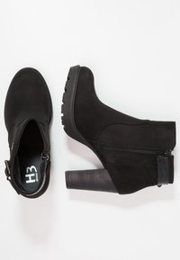 Bottines noires en daim, dotées d'un talon épais texturé, d'une fermeture éclair sur le côté et d'accents contrastants lisses.