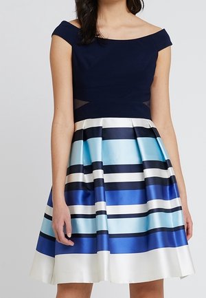 Une robe sans manches avec un haut ajusté bleu marine et une jupe évasée arborant des rayures horizontales dans des nuances de bleu, de blanc et de bleu marine.
