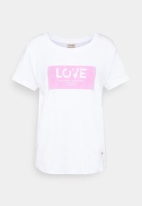 Vit bomullströja med rund halsringning. Har ett rosa rektangulärt grafiktryck med ordet "KÄRLEK" och ytterligare text nedanför.