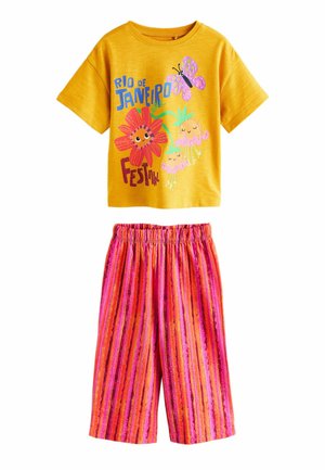 Żółta koszula z krótkim rękawem z kolorowym nadrukiem "Rio de Janeiro Festival", połączona z różowo-pomarańczowo-czerwonymi pasiastymi spodniami z elastycznym pasem.