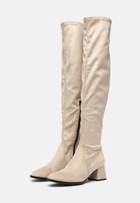 Botas de ante beige hasta la rodilla, con cremallera lateral, punta afilada y tacón cuadrado para mayor estabilidad.