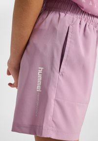 Lichtpaarse short met elastische tailleband, zijzak en reflecterend "hummel PERFORMANCE" logo aan de onderzijde. Soepele stoftextuur.
