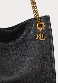 Bolsa de mão em couro preto com superfície texturizada, ferragens em tom de ouro, alça de corrente e um detalhe com o charme do logótipo R.L.