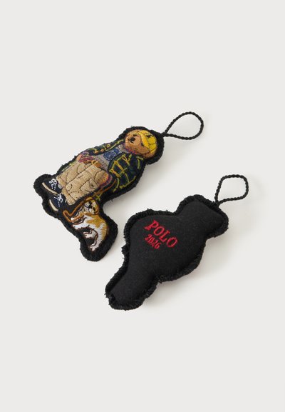Deux petits porte-clés en tissu avec des boucles ; l'un montre un ours en tenue décontractée avec un chien, l'autre est noir avec un texte rouge "POLO 2016".