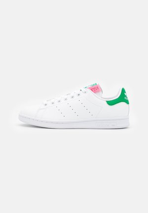 White Adidas Stan Smith sneaker with green heel tab, perforated side stripes, white laces, and pink and green tongue label.