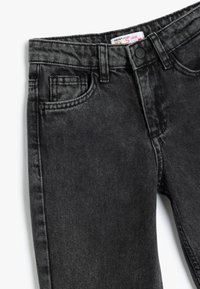 Mustat farkut, joissa on löysä malli. Ominaisuuksia ovat vyötärö, jossa on nappi, etutaskut ja ommellut yksityiskohdat. Sujuva pinta.