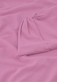 Zacht roze stof met een lichte glans, voorzien van een gedraaide knoopdetail in de hoek, wat een lichtgewicht en flexibele textuur suggereert.