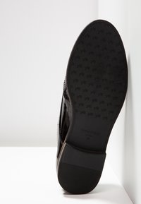 Semelle en cuir verni noir avec un motif de grip texturé. Présente une finition lisse et des détails de logo discrets, se rétrécissant vers le bout.
