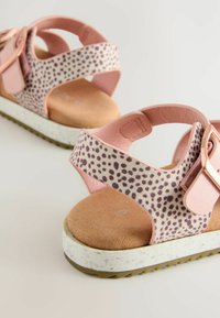Sandali rosa e maculati con una morbida soletta in suede, cinturino regolabile e una suola bianca testurizzata con piccole macchie di colore.