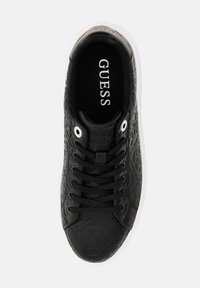 Sneaker nera con design in rilievo, tomaia in tessuto, lacci piatti, occhielli in metallo e suola in gomma bianca. Logo "GUESS" visibile all'interno.