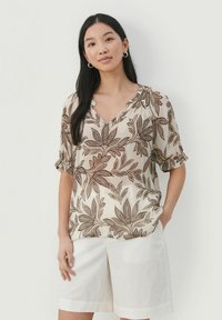 Bluse med blomsterprint i creme- og brunnuancer, der har en V-udskæring og korte, rullede ærmer. Blødt, let materiale.